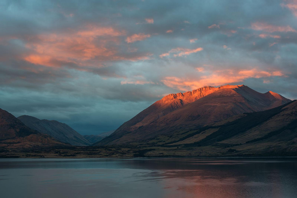 mountains during sunrise near the waterway in NZ