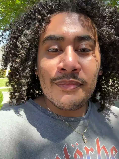 Me talking to the camera from my front yard. My curly hair is down and my brown skin is thriving. 