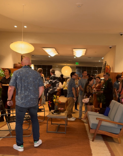 Group of people standing in Metas new Waikiki store near a seating area. High end audio equipment and various version of their camera glasses