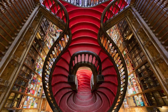 A gorgeous set of stairs in a library, organic in shape and deep red